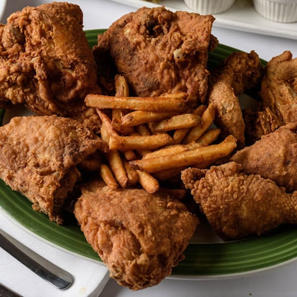 Crispy fried chicken pieces and golden french fries served on a green-striped plate.